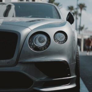 front of a grey bently parked in the street