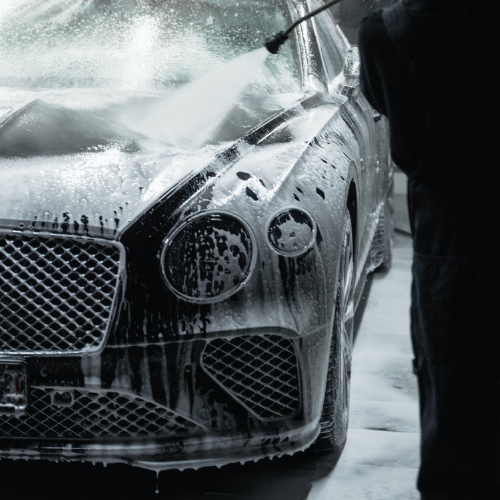 Bentley luxury car being pampered with foam detailing by a professional in a garage setting. This photo was taken in chelsea.
